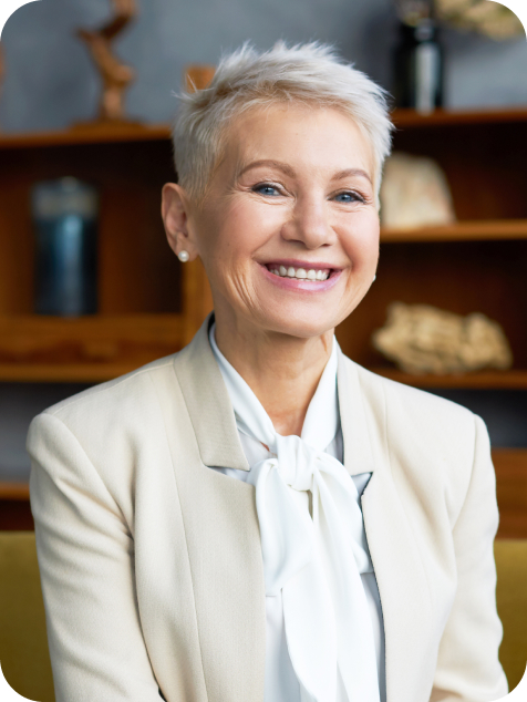 A professional woman with short white hair wearing a white blazer.